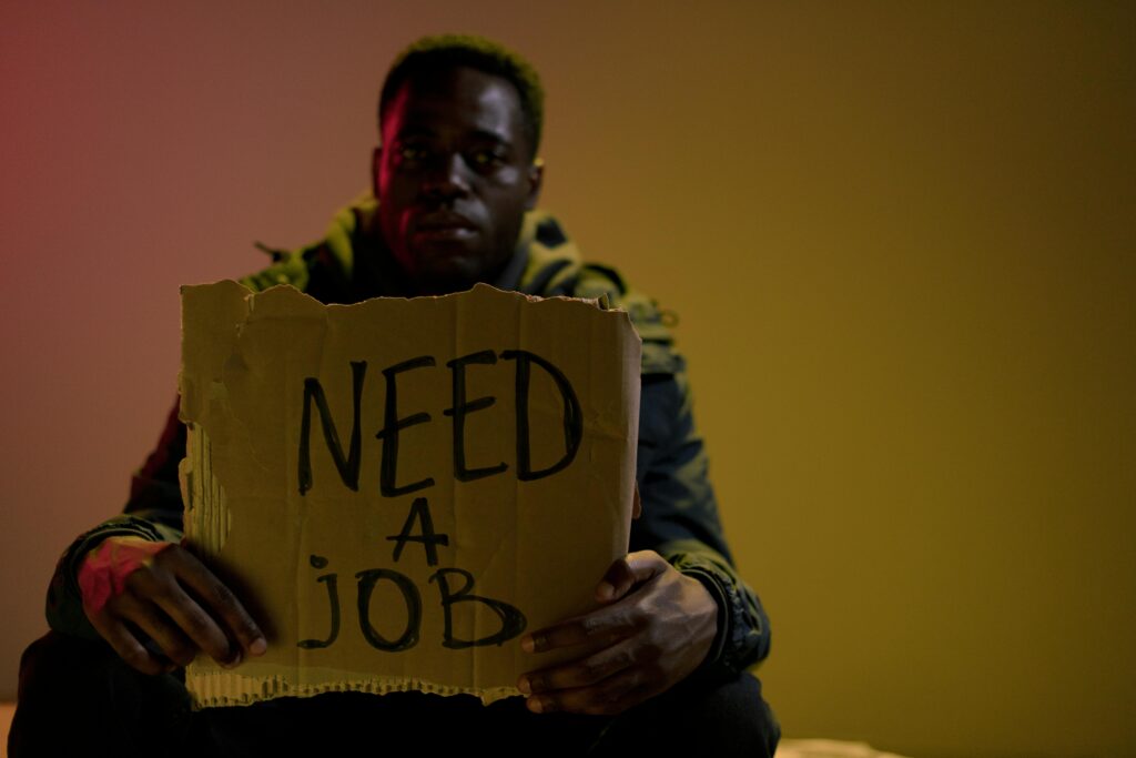 Man with a cardboard sign seeking employment, highlighting unemployment and social issues.